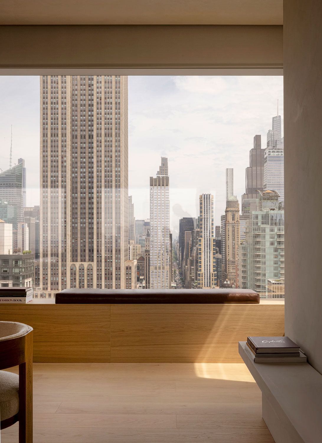 Built-in oak window seat at 262 Fifth Avenue overlooking the Manhattan skyline through expansive floor-to-ceiling glazing
