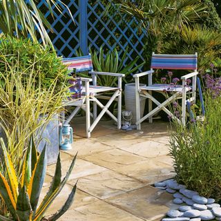 Sand coloured concrete paving stones with plants and garden chairs