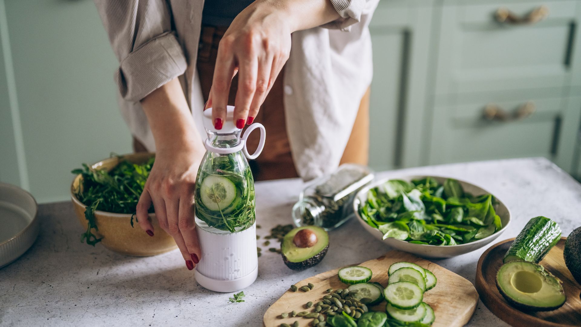 Woman making detox smoothie with cucumber and spinach