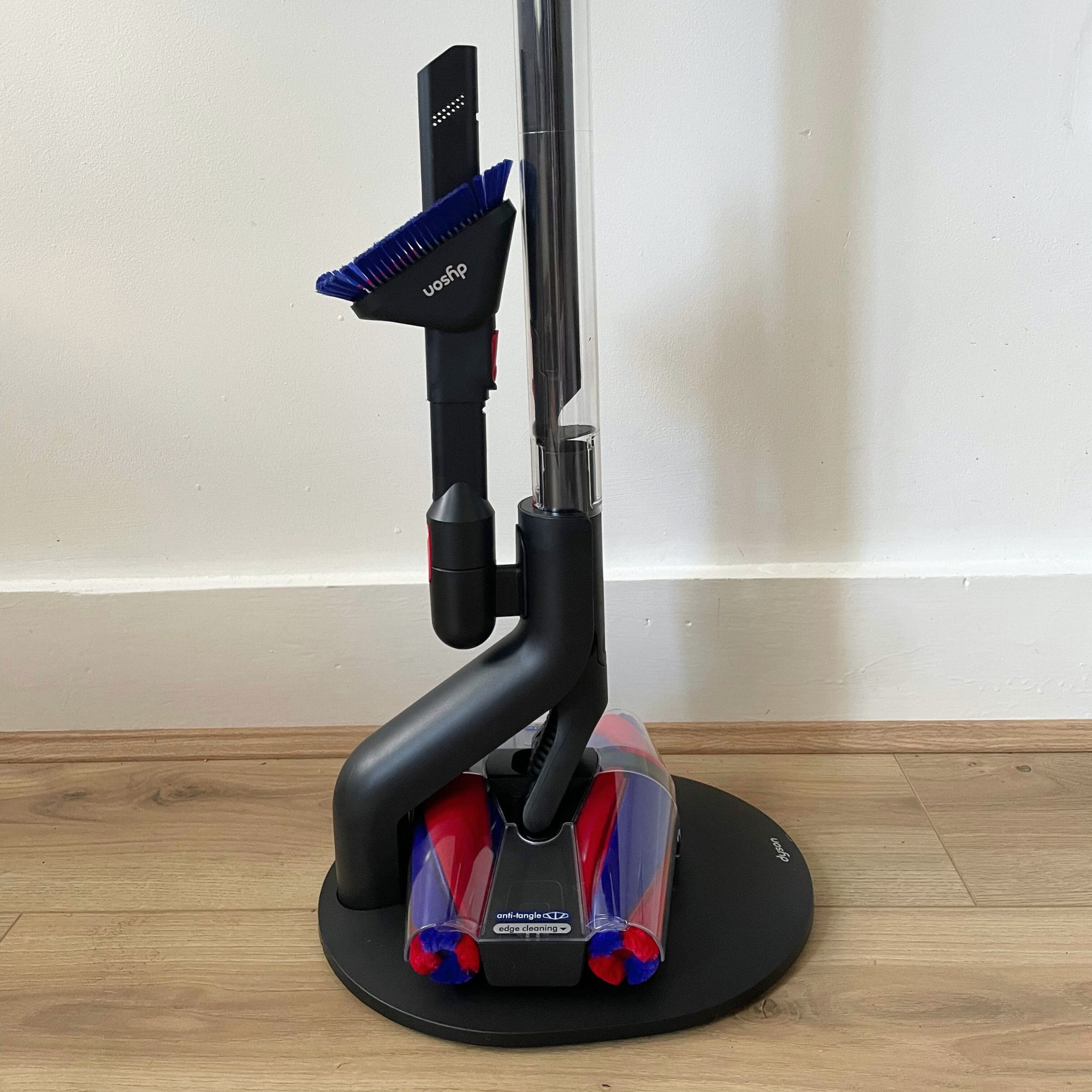 Dyson PencilVac stand with the vacuum and accessory on it, standing on wood-effect flooring