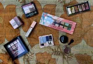 A selection of drugstore eyeshadows on a tan, floral blanket