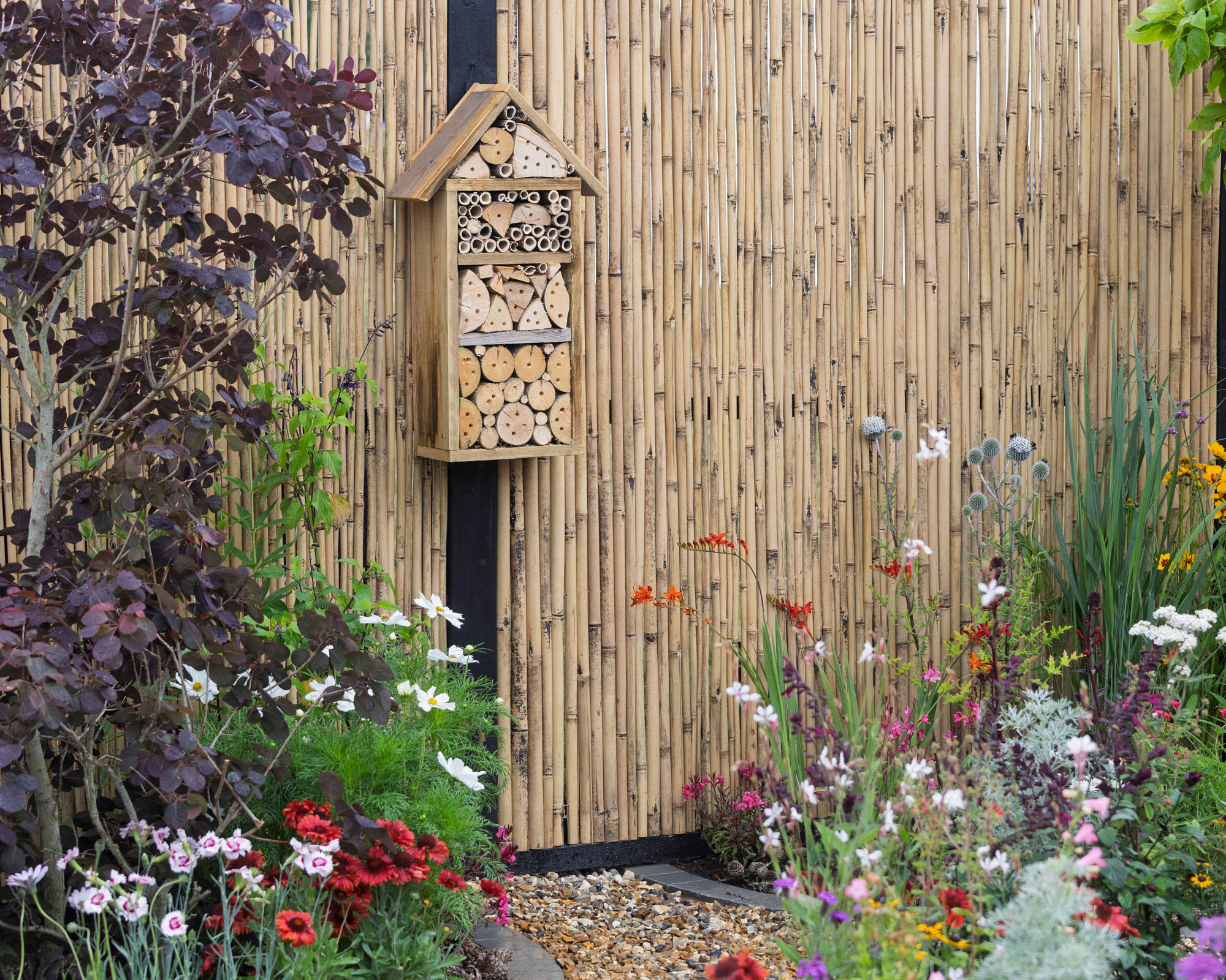bamboo pole cladding for fence with insect house and flowerbeds
