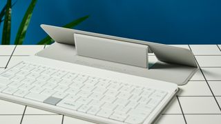 a picture of the stand on a white, lightweight tablet keyboard made by mokibo rests upon a white tiled table with a blue background