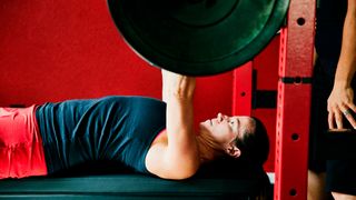 Woman performs bench press using a barbell