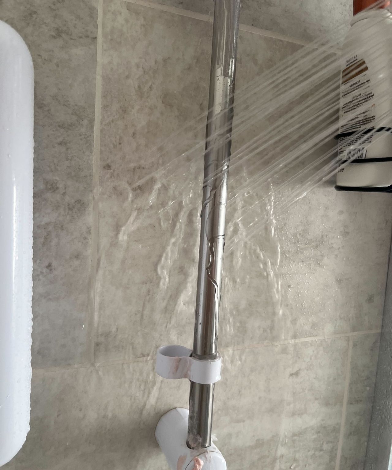 Rinsing the metal bar of a shower head with water