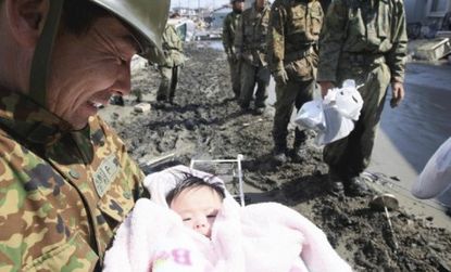 A soldier smiles at the four-month-old baby girl who was rescued from beneath a pile of debris three days after the quake hit.