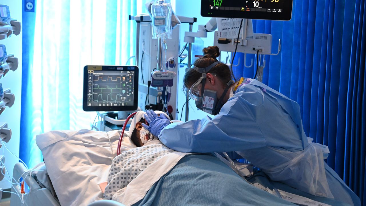 A nurse wearing PPE cares for a patient in intensive care