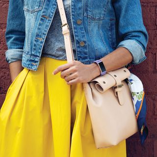 A woman in a yellow skirt wearing a purple Fitbit