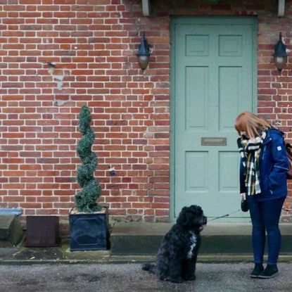 brown brick house with dog and women