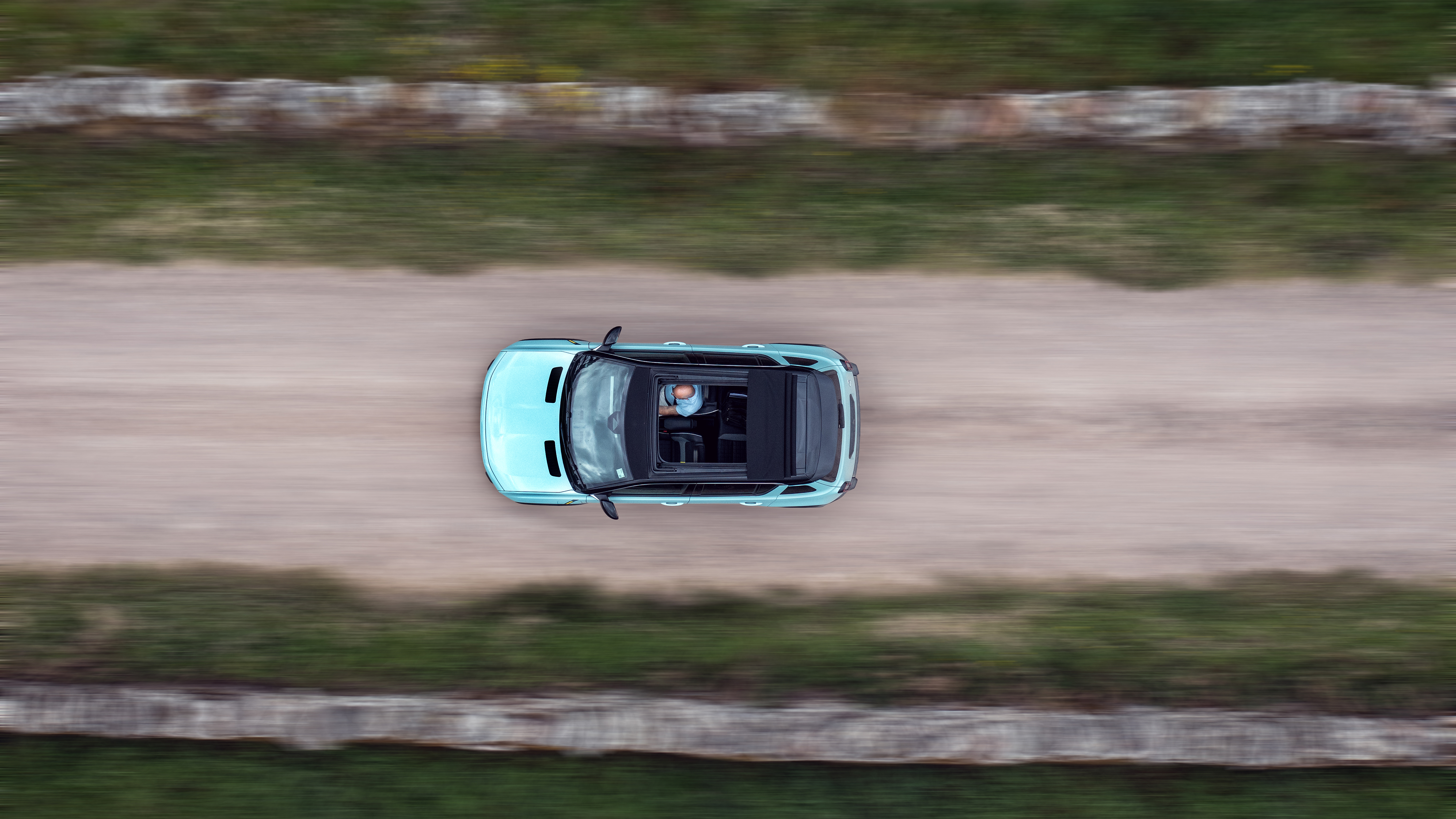 A top-down shot of an electric car driving through the countryside