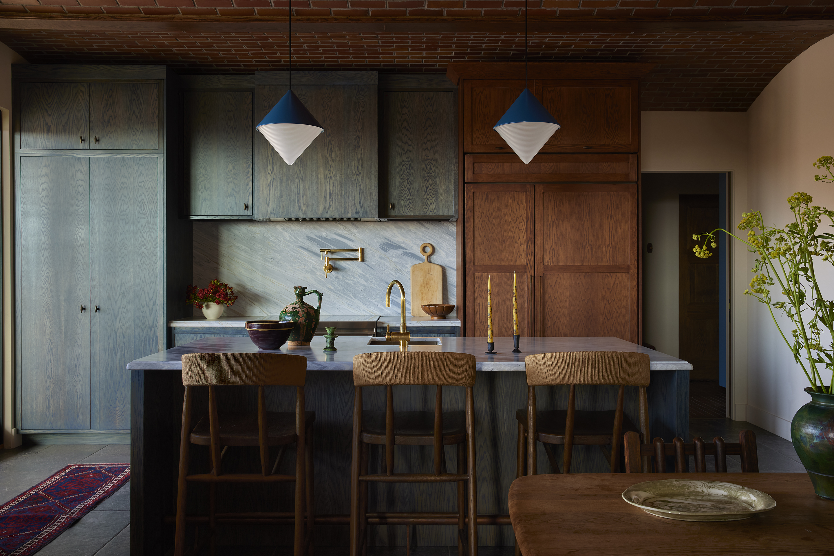 a kitchen with a dark blue stained timber cabinet, an island, and angular ceiling lights