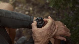 A photo of a man in the woods wearing a Garmin Fenix 8 Pro, using it to check his ECG heart health data.