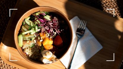 Bowl of nutritious foods, including cous cous, cabbage and cucumber on a restaurant tray with dappled sunlight, representing how to lose weight without exercise