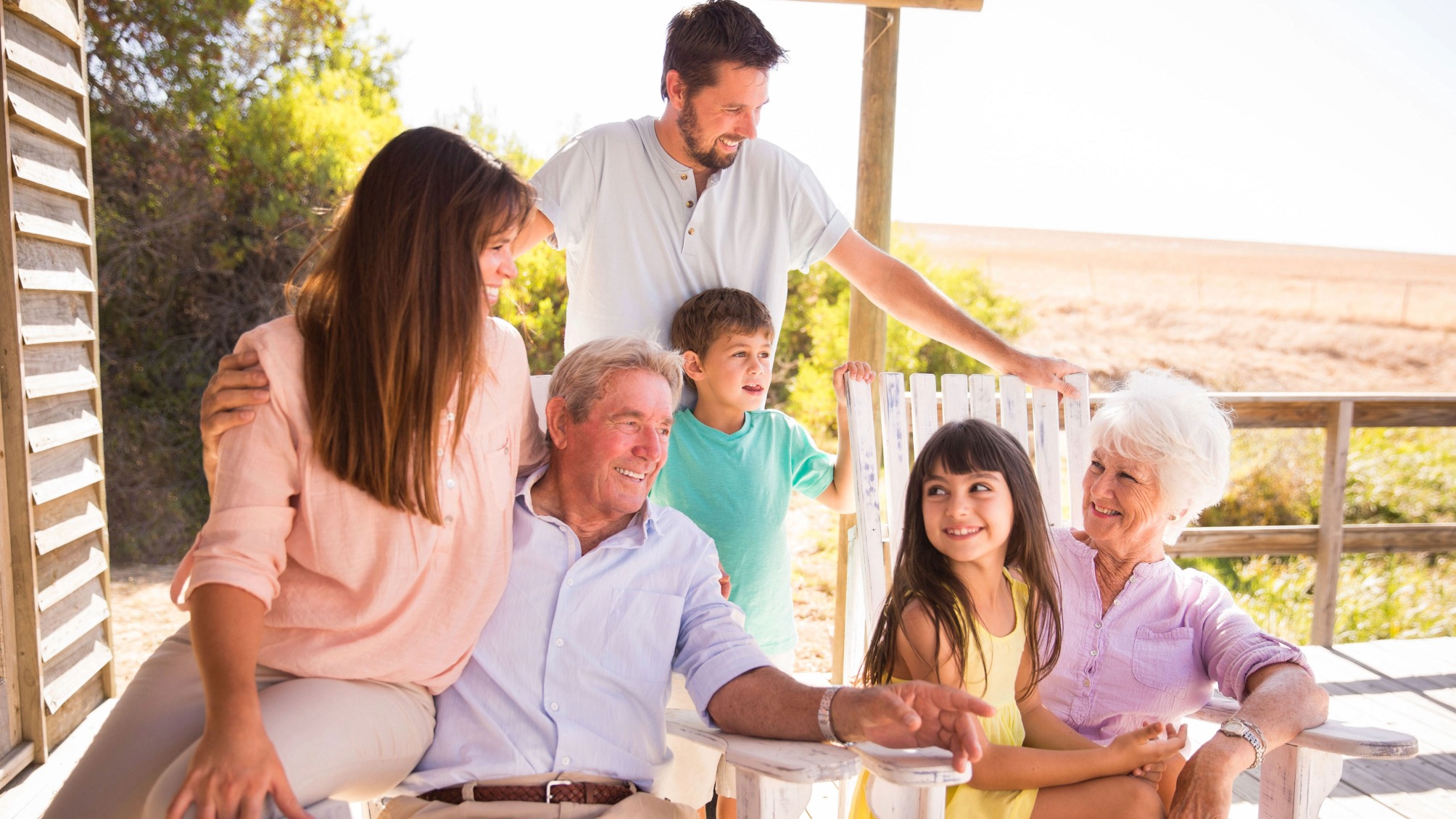 Three generations of a family sitting on a porch in summertime