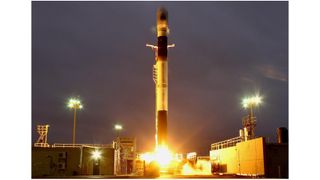 a white and black rocket launches at night.