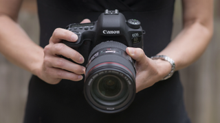 En person som holder et kamera av typen Canon EOS 6D Mark II.