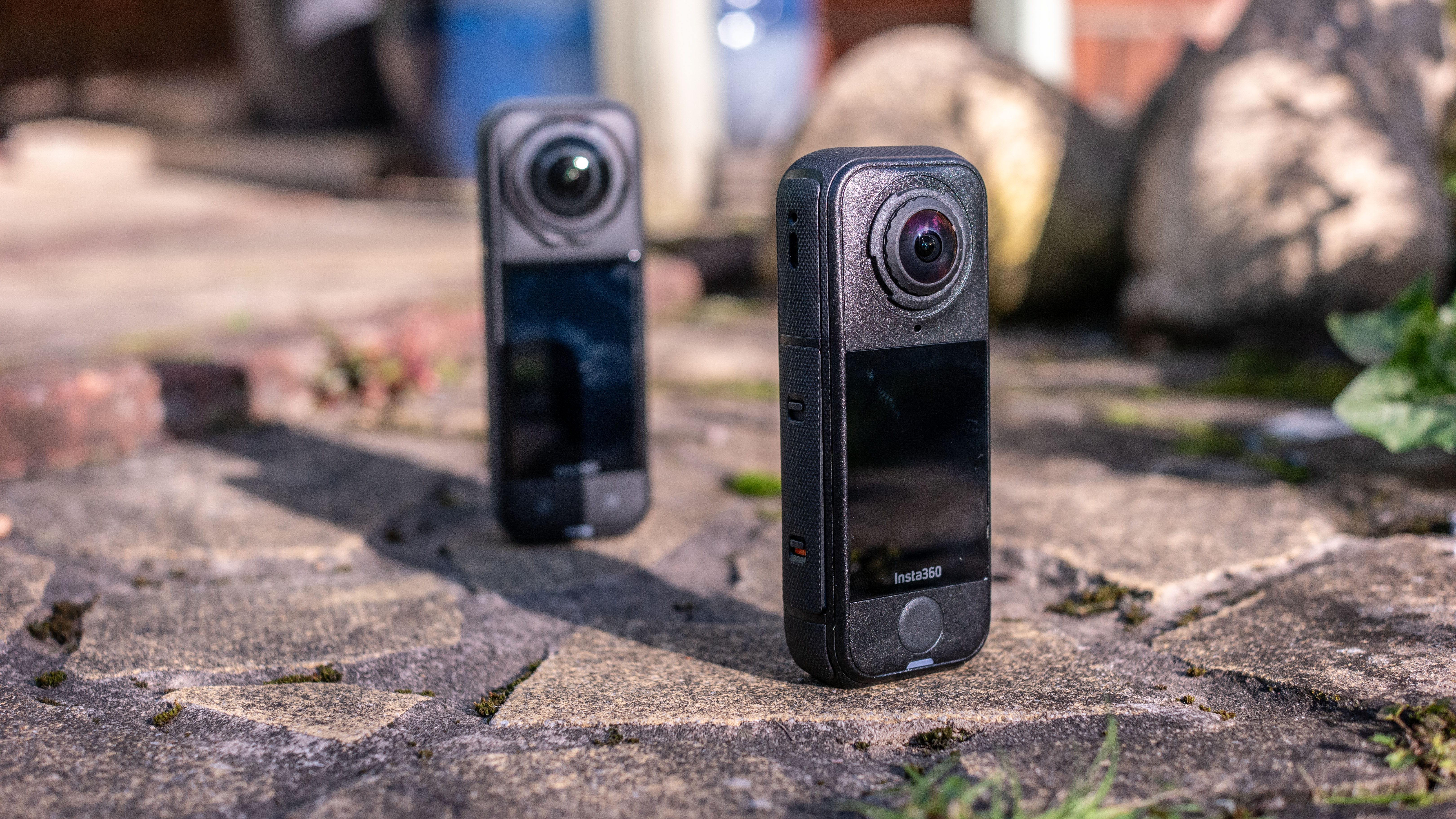 The Insta360 X5 and X4 Air action cameras in an outdoor setting under natural light