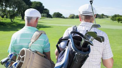 A pair of golfers talk as they walk together.