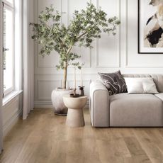 Living room with white wall panelling, grey sofa, wood effect LVT flooring and tree in pot