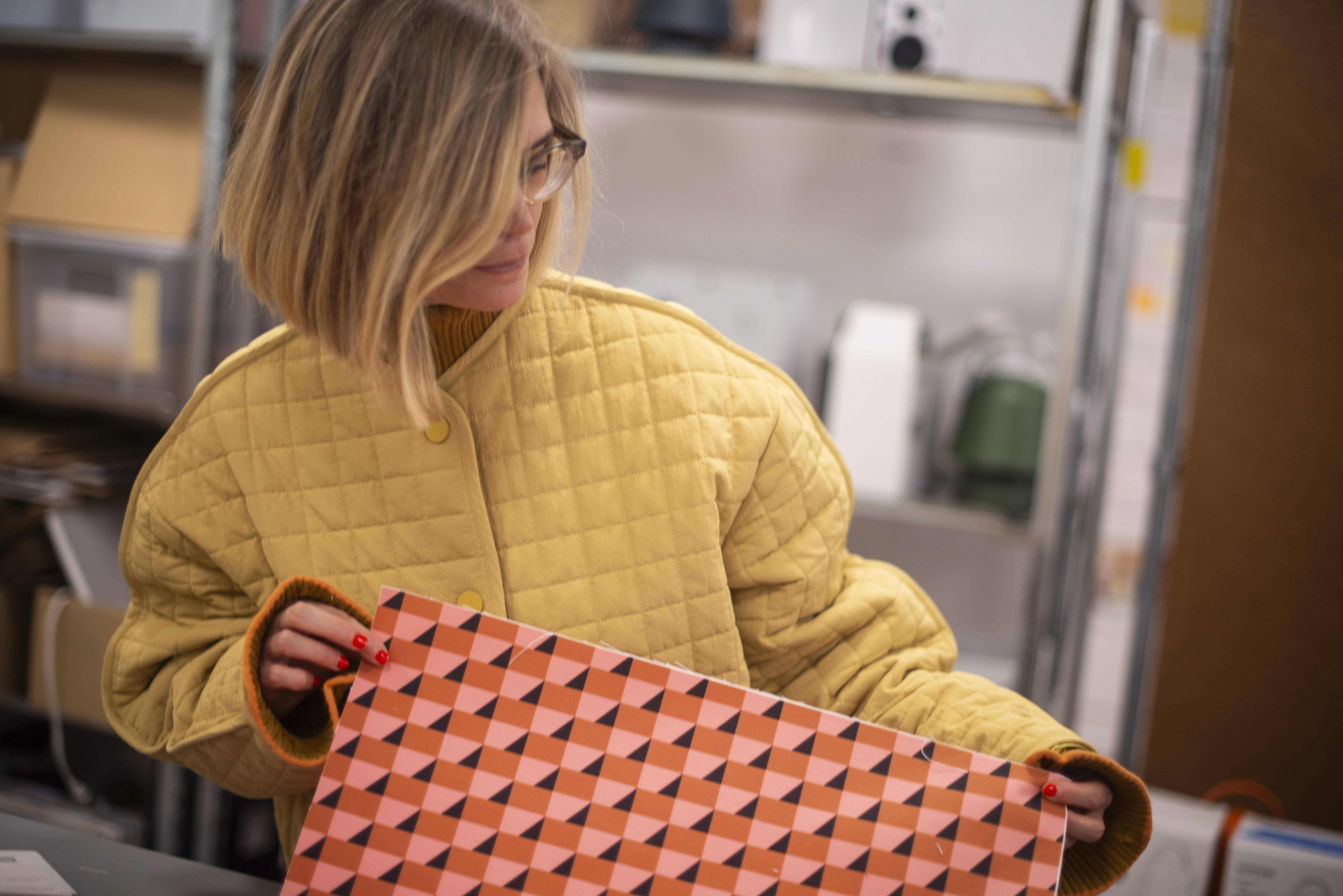 Swedish designer Teklan examining pattern samples in a factory