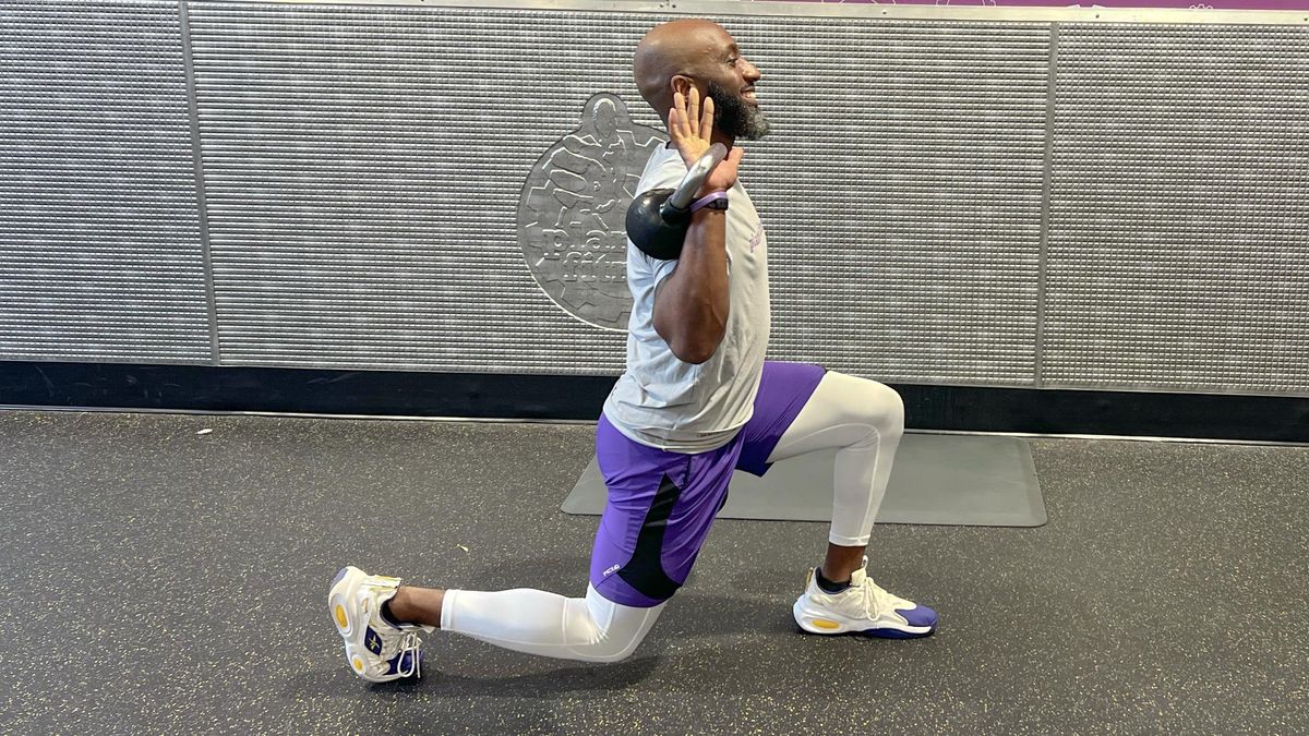 Teddy Savage performing an alternating reverse lunge to overhead shoulder press