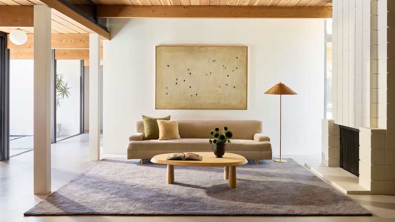 modern and miniamlist home with short shag rug in gray color, with beige sofa, round timber coffee table, floor lamp, and brick fireplace