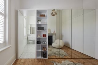 A mirror-fronted bespoke wardrobe that opens to reveal shelving
