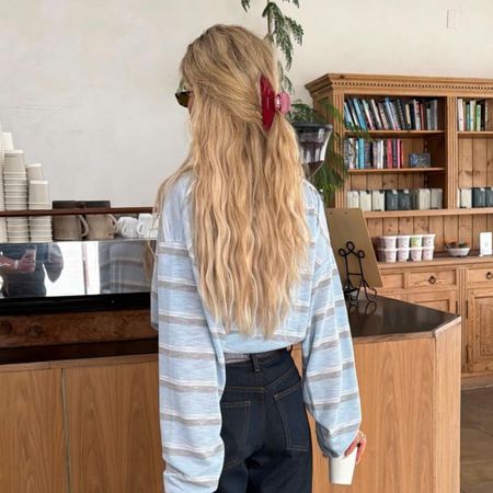 Creator @emilisindlev ordering a coffee with her long, wavy hair in a claw clip