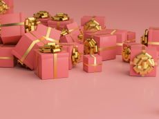 A stack of gifts in pink wrapping paper with gold bows