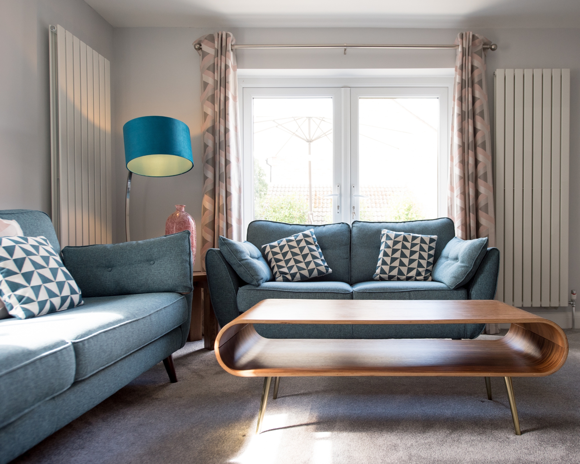 Retro living room with blue sofas, slick wooden coffee table and light from back window