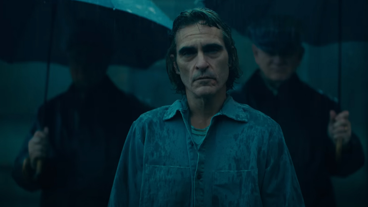 Arthur Fleck looks up to the rain-filled sky as he's flanked by two prison guards in Joker 2