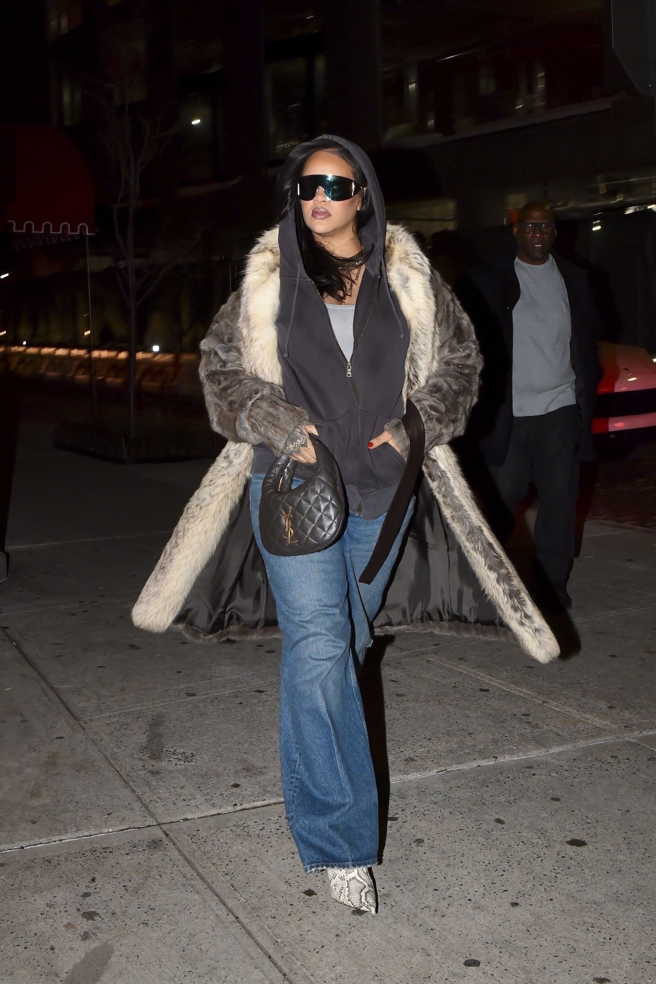 Rihanna layered an oversize hoodie underneath a Saint Laurent fur coat with flared jeans