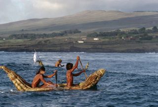 Two men wearing body paint row a canoe as part of a race during Easter Island's Tapati Festival