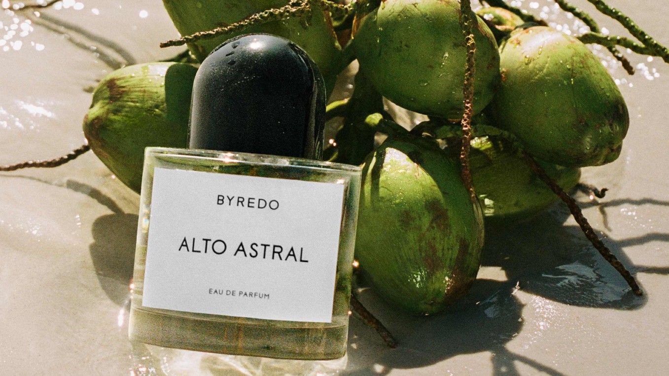 a bottle of perfume next to a pile of coconuts
