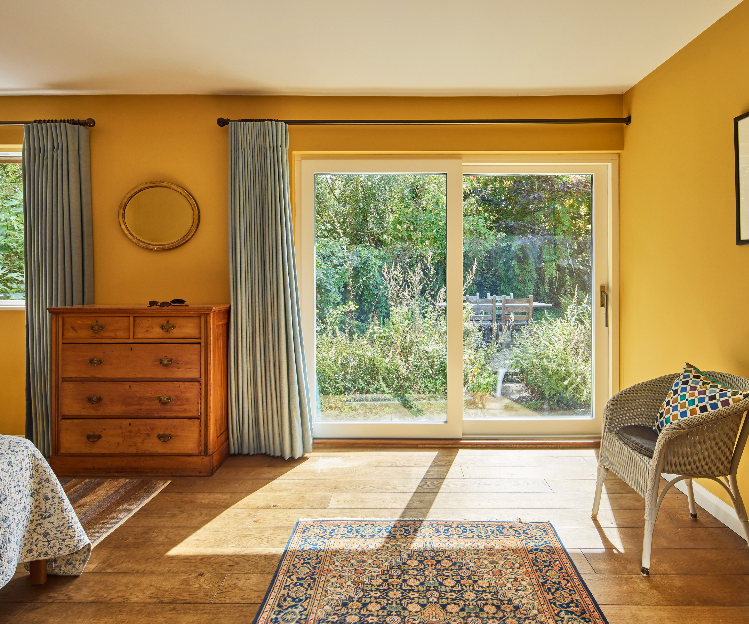 Bedroom with mustard yellow walls and sliding doors leading onto garden