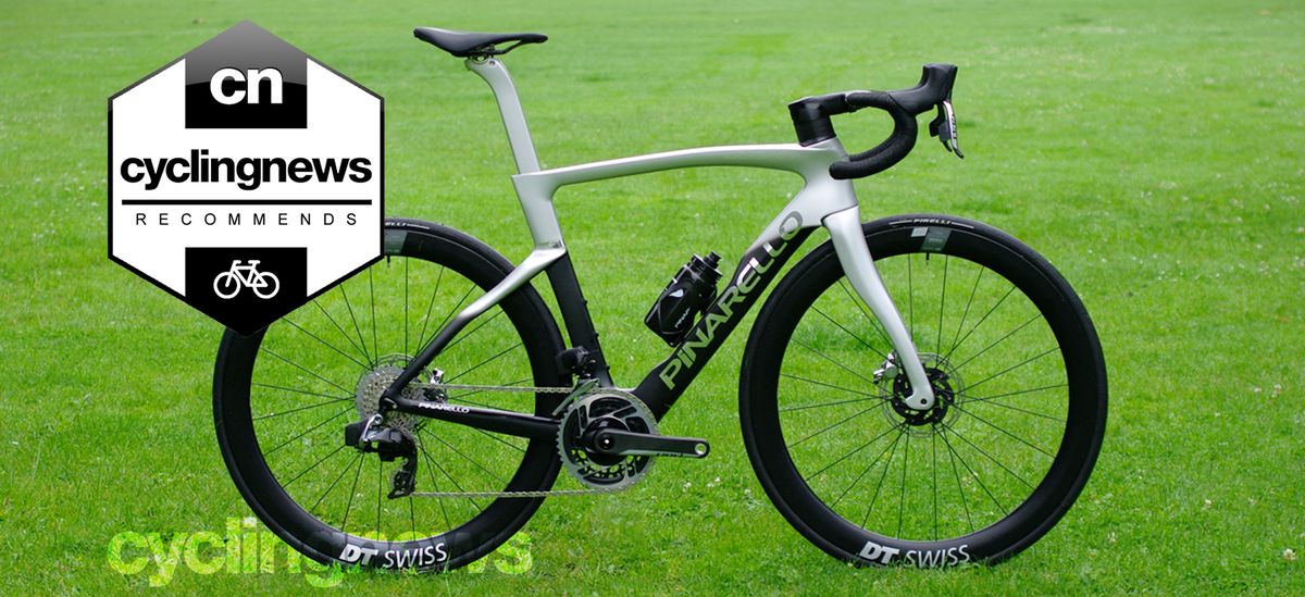 A black and silver Pinarello Dogma F, complete with SRAM Red groupset and DT Swiss wheels sit, stands on a grass surface, with a &#039;recommends&#039; badge overlaid