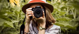 Woman wearing a hat holding a pro camera in the woods
