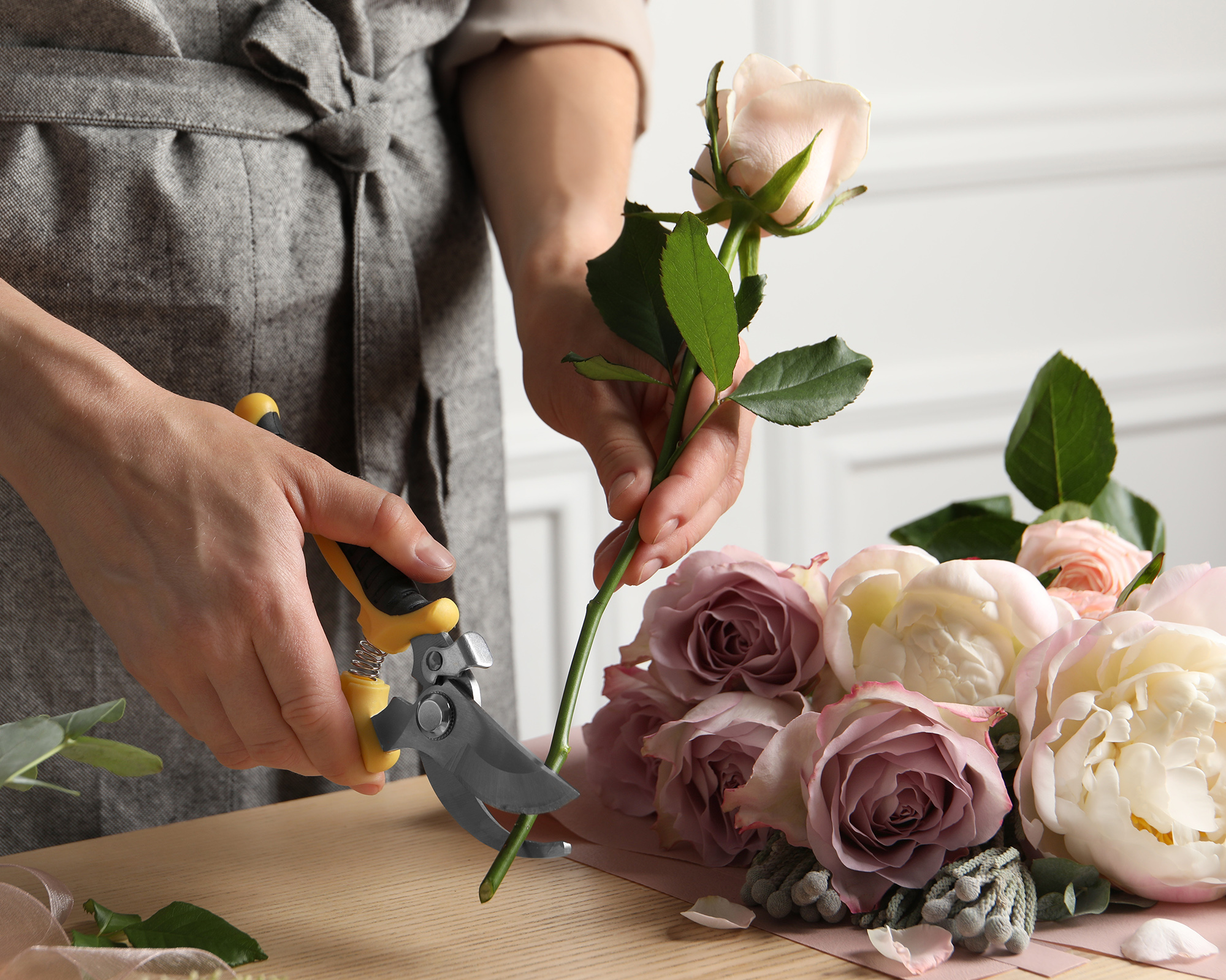 Florist cutting flower stem with pruner at workplace, closeup