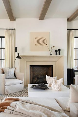 Living room with beige fireplace and wall art, white sofas and black accessories