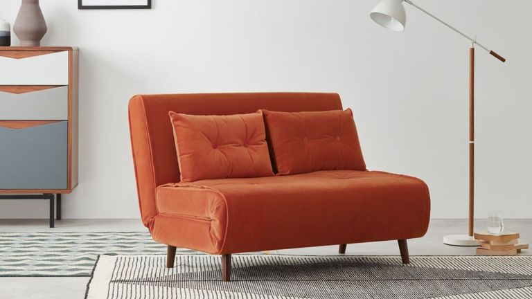 MADE Haru Small Sofa bed in Tangerine Orange Velvet colour in living room with white walls, floor lamp and white and black rug