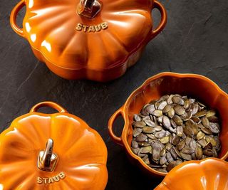 Ceramic pumpkin pots, one open with pumpkin seeds