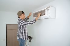 A young man inspecting his air conditioner