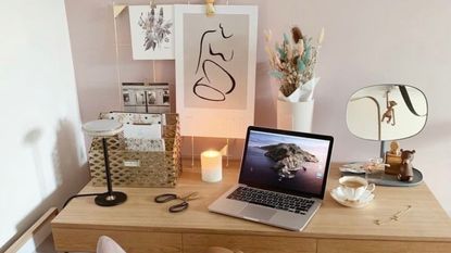 Desk with laptop, candle, and wall art