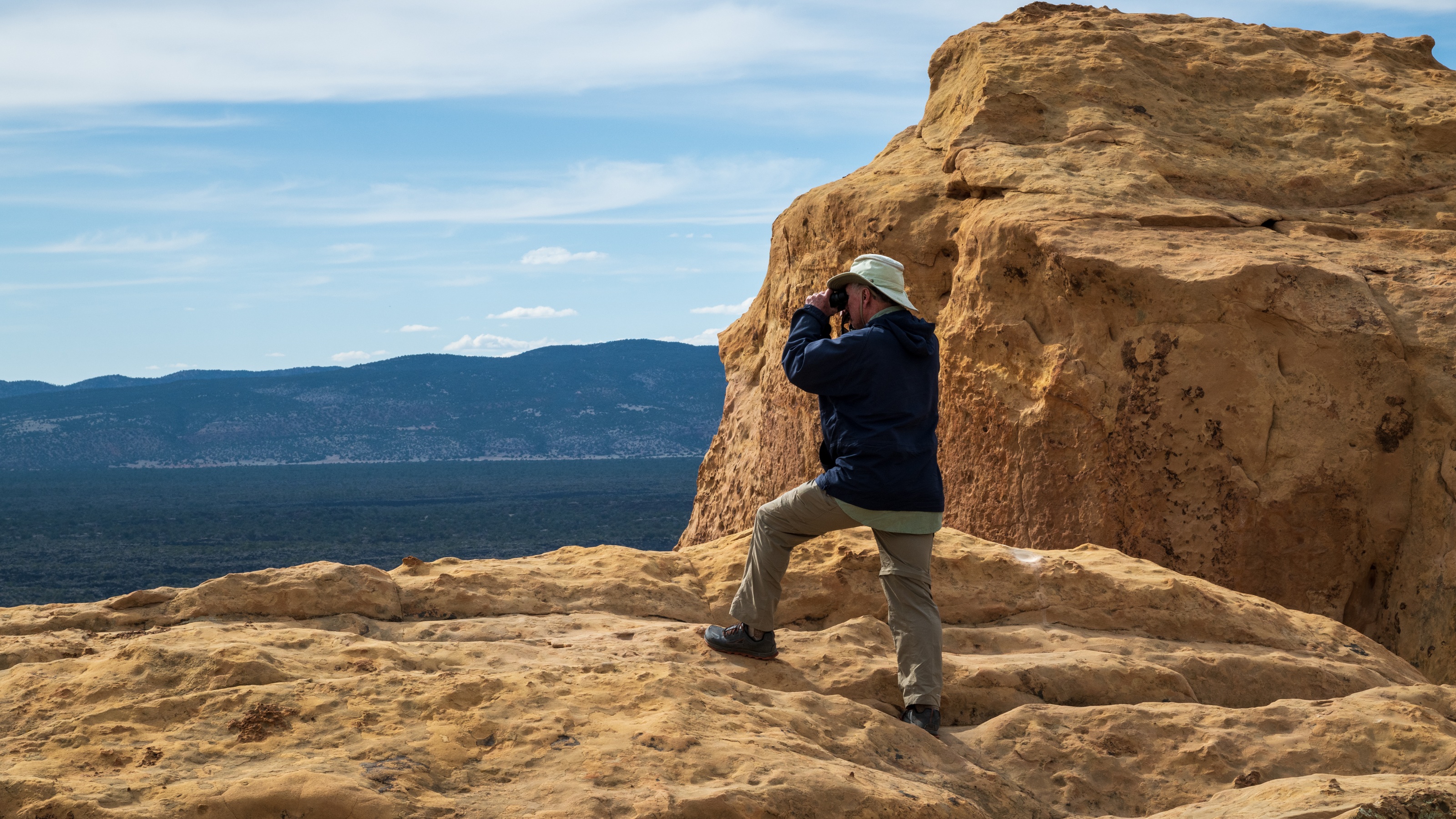 A man looks into the distance with binoculars in New Mexico.