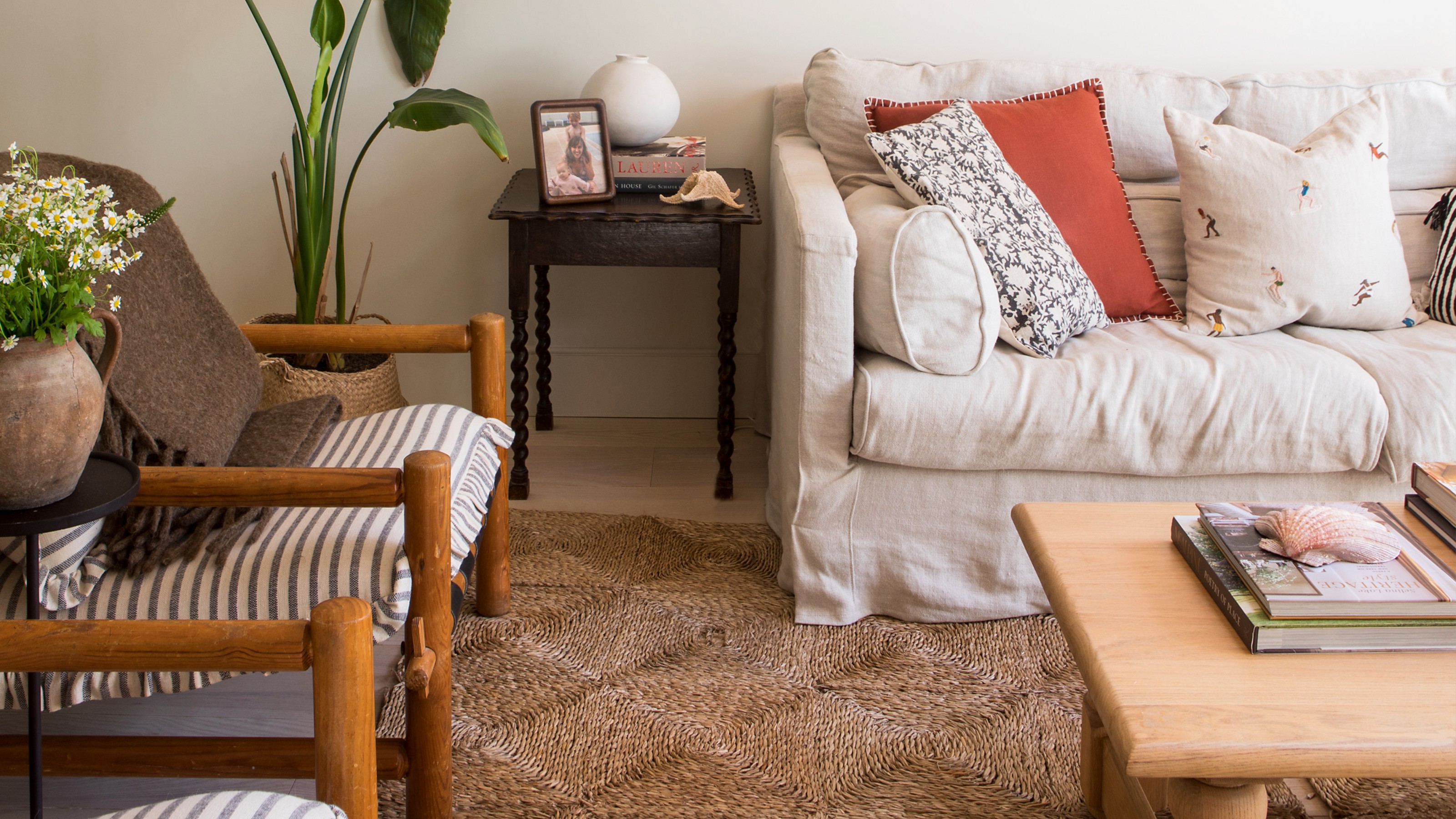 A living room with a cream loose cover sofa and a jute rectangular rug underneath