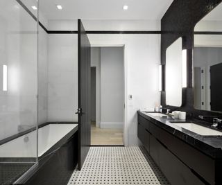 black and white bathroom with black bath and black vanity unit and double mirrors