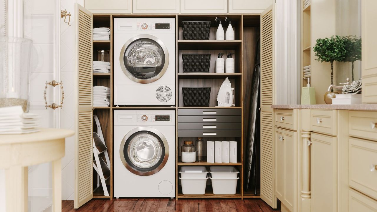 A laundry room with stacked washing machine and dryer, shelves beside them with laundry products and baskets