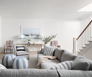 family room with cream walls and gray sectional and staircase in background