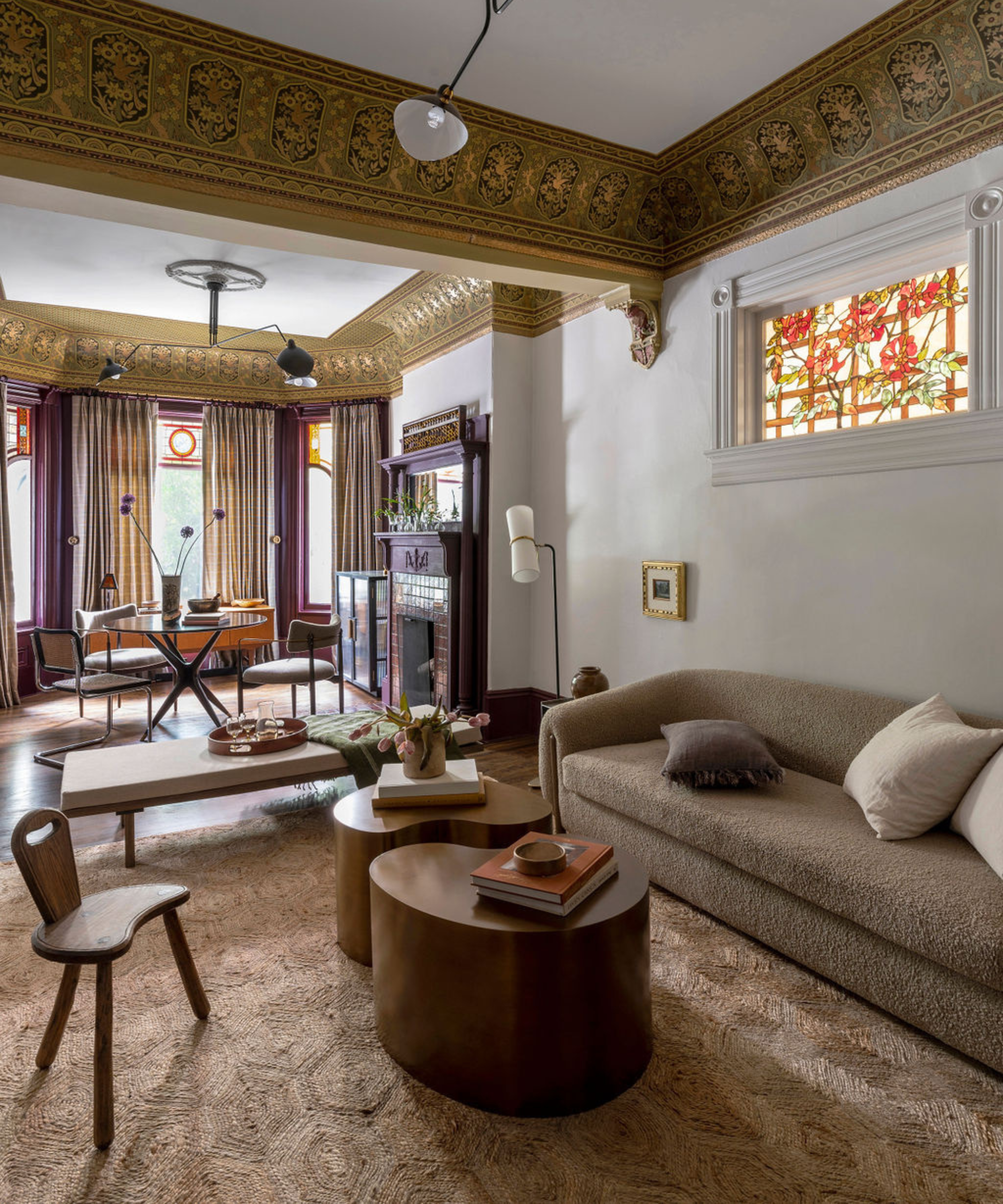 a living and dining area in a home with gold and purple color details, detailed moldings, stain glass windows, and a large jute rug on the floor