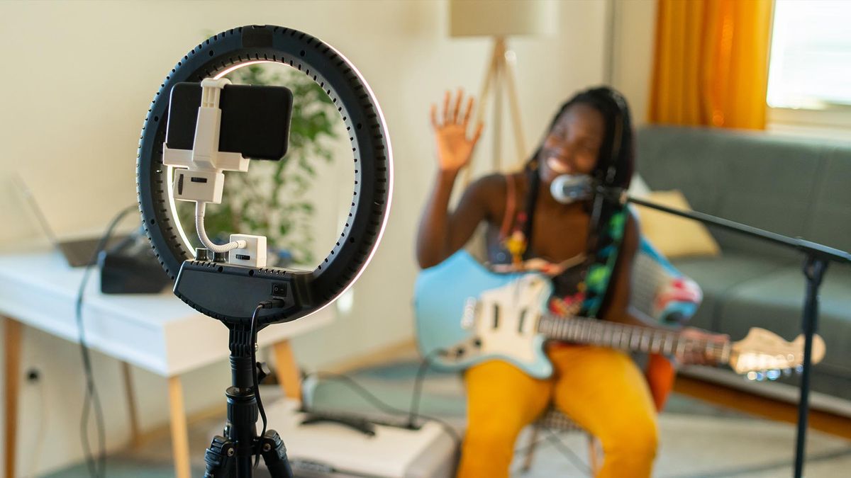 Woman recording herself playing guitar